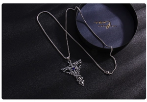 Detail of gothic snake cross necklace with blue gemstone and polished steel finish