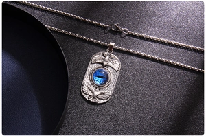 Macro detail of silver eagle pendant with blue evil eye stone on black leather