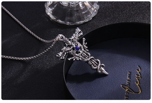 Macro detail of gothic cross sword pendant with blue gemstone and dragon relief