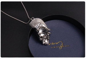 Détail d'un pendentif crâne argenté avec un casque de spartiate sur un plateau de luxe