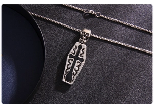 Macro detail of gothic coffin pendant with black cross and skull on steel box chain