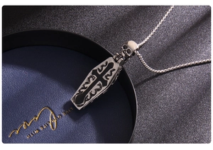 Macro shot of Gothic coffin cross pendant with skull detail on navy jewelry tray