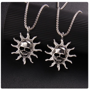Close-up of retro silver skull sun pendant with vintage texture on steel box chain
