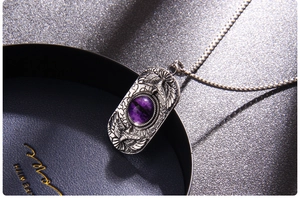 Macro shot of silver eagle necklace with purple cat eye stone and box chain details