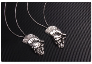 Détail du pendentif crâne avec casque romain en argent vieilli sur fond texturé sombre