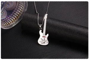 Detail of silver guitar pendant with red accents and intricate leaf engraving on black roll
