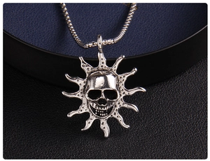 Macro shot of silver flame skull pendant and metal snake chain on dark leather display