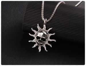Macro shot of gothic flame skull pendant with sun rays and silver box chain on leather