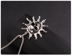 Macro detail of gothic skull pendant with flame sunburst design on a silver box chain