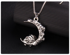 Gros plan d'un collier croissant de lune argenté avec crâne gothique et texture de cratère