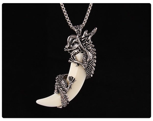 Macro view of a vintage silver dragon coiled around an off-white wolf tooth pendant