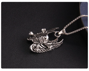 Macro shot of punk skull with angel wings pendant on a box chain over black leather