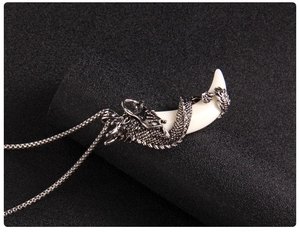 Detailed view of an intricate silver dragon coiled around a white wolf fang pendant