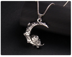 Gros plan du pendentif croissant de lune argenté avec crâne et texture de cratère réaliste