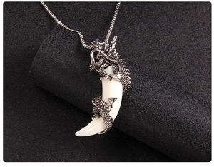 Macro detail of retro dragon wrapping around a curved fang pendant on a silver square chain