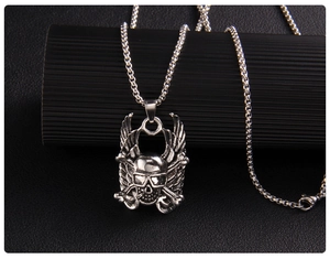 Macro detail of silver skull pendant with wings and crossbones on textured stand