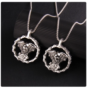 Close-up of silver gothic skull engine pendant with heavy metal chain on black texture