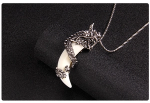 Detailed close-up of a silver dragon pendant wrapped around a white wolf tooth
