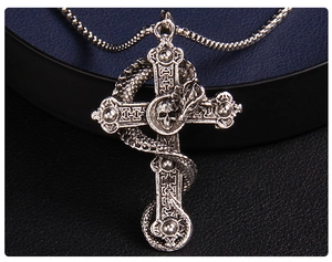 Macro detail of gothic stainless steel dragon cross pendant with skull and beaded chain
