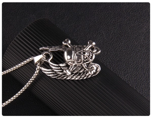 Macro shot of vintage skull pendant with angel wings on stainless steel box chain