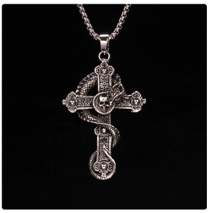 Macro detail of gothic cross pendant with coiled dragon and skull in vintage silver finish
