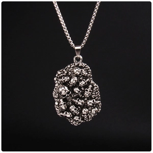 Détail macro du pendentif punk gothique en argent avec crânes empilés et chaîne de boîte
