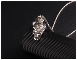 Macro d'un pendentif crâne en acier avec chapeau haut-de-forme sur socle noir rayé