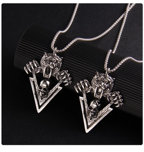 Vue détaillée des pendentifs tête de tigre et crâne en argent vintage avec finition vieillie