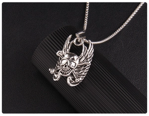 Macro side view of a punk winged skull pendant with sunglasses on a silver chain