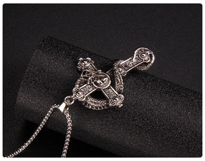 Macro detail of gothic cross pendant with coiled dragon snake and skull on black leather