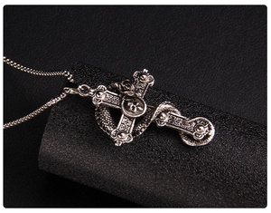 Detailed close-up of gothic cross pendant with skull and snake wrap on black stand