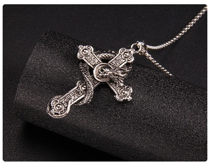 Macro shot of a retro stainless steel dragon wrapped around a gothic cross pendant