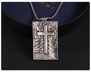 Détail d'un pendentif croix argenté vintage avec une finition en métal martelé