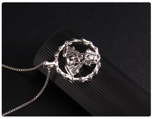 Detail of vintage silver skull engine pendant with motorcycle chain on a box chain