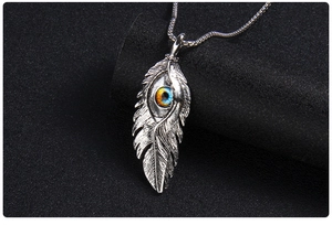 Vue macro du pendentif plume argentée vintage avec œil maléfique bleu sur chaîne