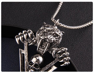Vue macro du pendentif tête de tigre et crâne avec griffes en acier inoxydable vintage