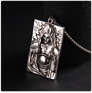 Gros plan sur un pendentif en acier vintage avec relief de personnage à capuche et croix