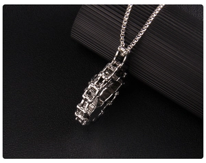 Close-up of industrial silver motorcycle engine pendant with heavy box chain on leather