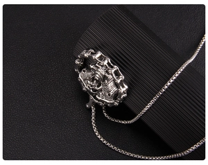Macro shot of silver motorcycle engine pendant on a box chain over black leather
