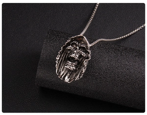 Macro shot of vintage silver skull pendant with dark gothic texture and bead chain