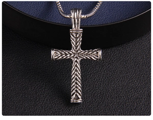 Dettaglio del ciondolo a croce in argento vintage con trama intrecciata su catena snake