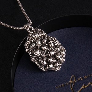 Collier punk gothique avec pendentif crânes sur plateau en cuir bleu, vue à 45 degrés