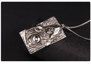 Vue macro d'un pendentif gothique argenté avec une figure mystérieuse sur cuir noir texturé
