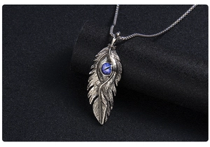 Détail macro du pendentif plume en acier inoxydable vintage avec œil bleu incrusté