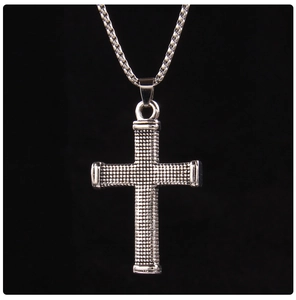 Macro detail of silver stainless steel cross pendant with dot matrix texture on box chain