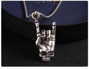 Macro shot of punk style skull pendant with rock gesture on vintage silver chain