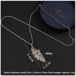 Détail du pendentif plume argenté avec œil maléfique jaune et chaîne en acier inoxydable