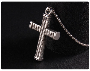 Macro shot of silver-tone stainless steel cross pendant with checkered texture pattern