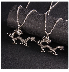 Detailed macro view of two silver dragon necklaces with intricate carved scales on black