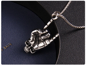 Macro detail of gothic punk skull hand gesture pendant on vintage steel chain
